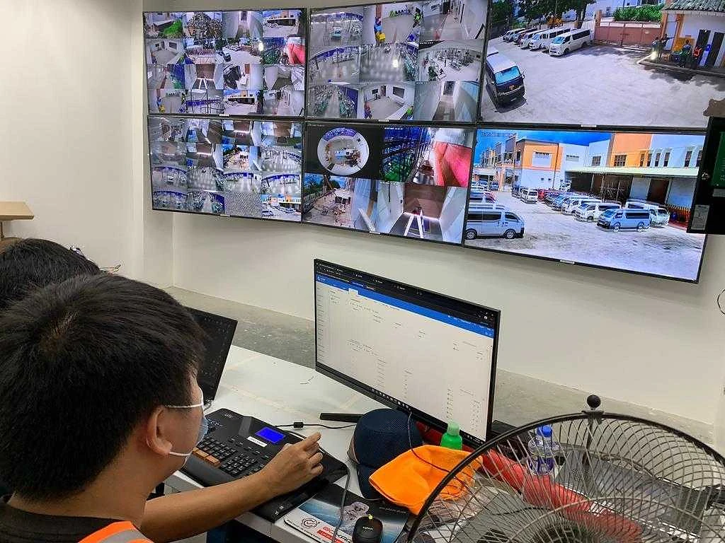 An operator at a monitoring station facing a wall of live feeds