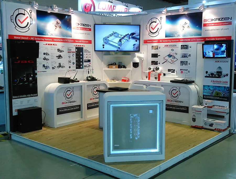 The earlier Gokaizen stand: a white booth of soldering stations, CCTV and barcode equipment