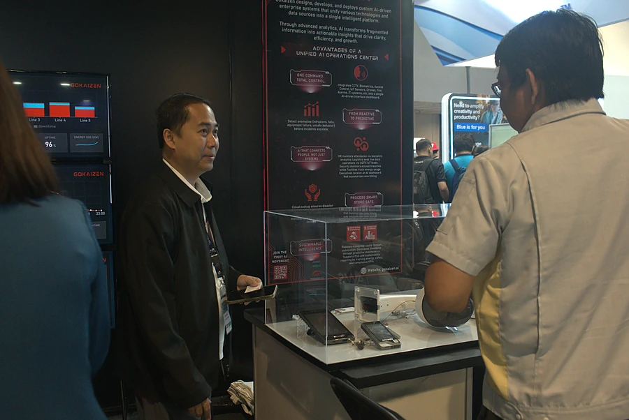 A Gokaizen engineer walking a visitor through the platform on a tablet at the stand