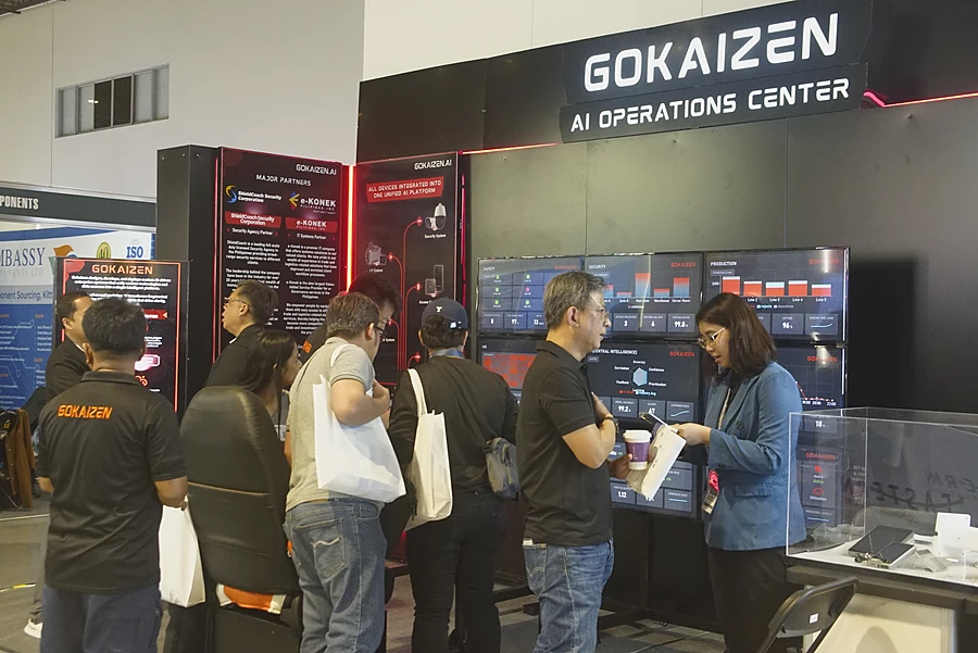 Visitors and Gokaizen staff at the PSECE stand, a wall of live dashboards behind them