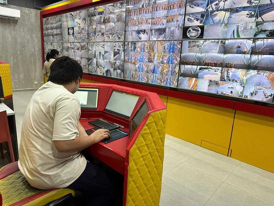 An operator at a console facing a dense wall of live camera feeds